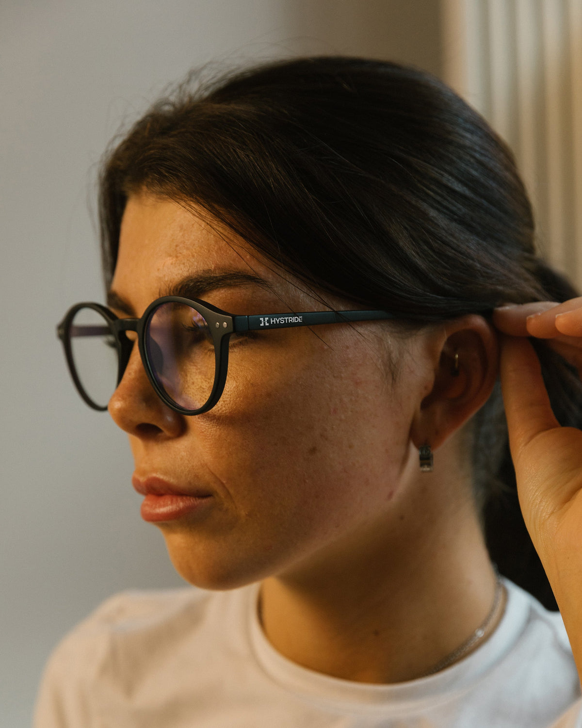 Person adjusting glasses with a neutral background